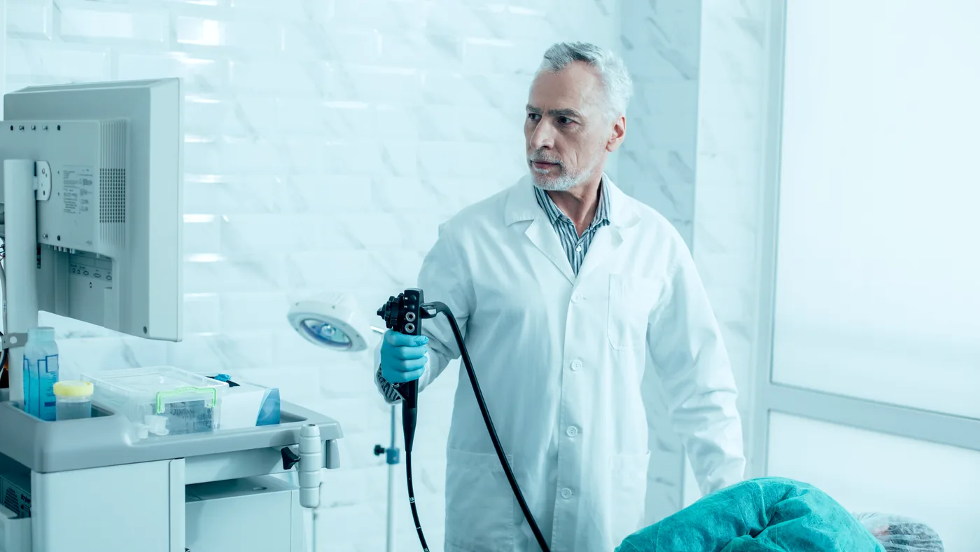 Médico com colonoscópio em sala de endoscopia · imagem ilustrativa